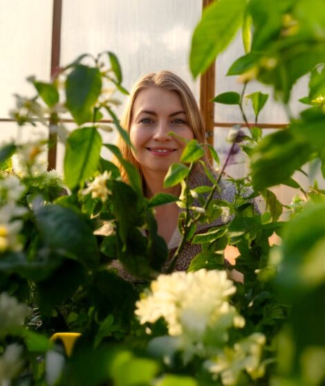 En ung kvinna mitt bland gräna växter i ett växthus.